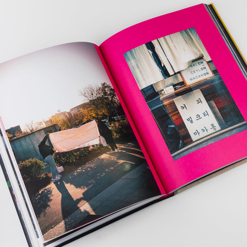 Open photo album with pink cover displaying images of a person and a building with Korean text.