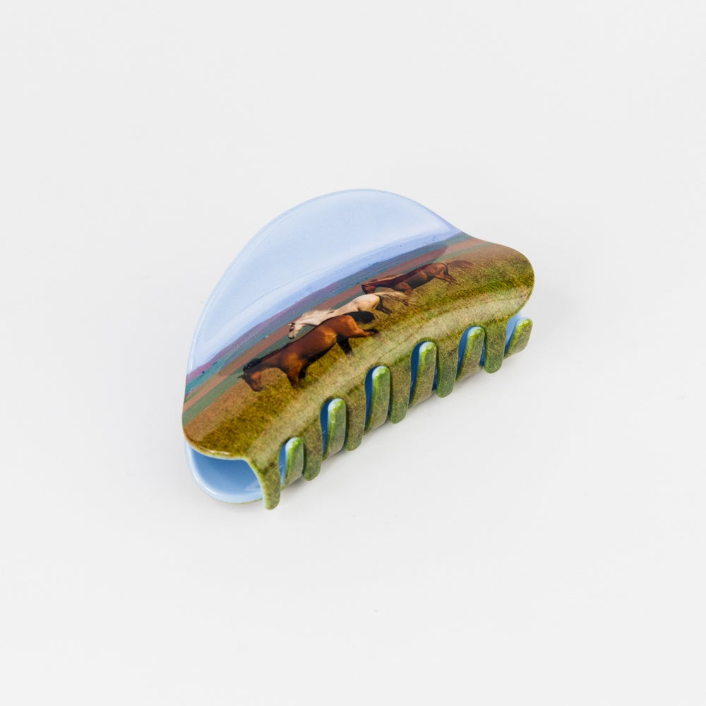 Hair clip with a scenic design of horses on a white background