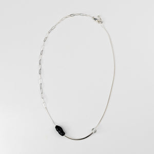Silver necklace with a black pendant on a white background