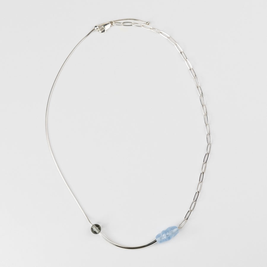 Silver necklace with a blue pendant on a light gray background