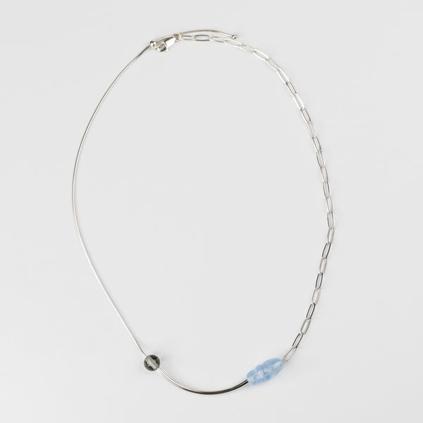 Silver necklace with a blue pendant on a light gray background
