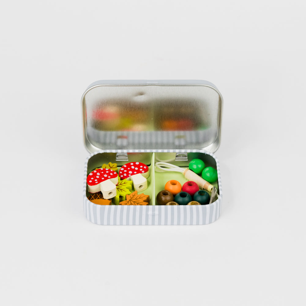 Small open tin with colorful miniature food items on a white background
