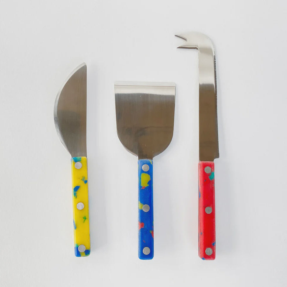Three cheese knives with colorful handles on a white background