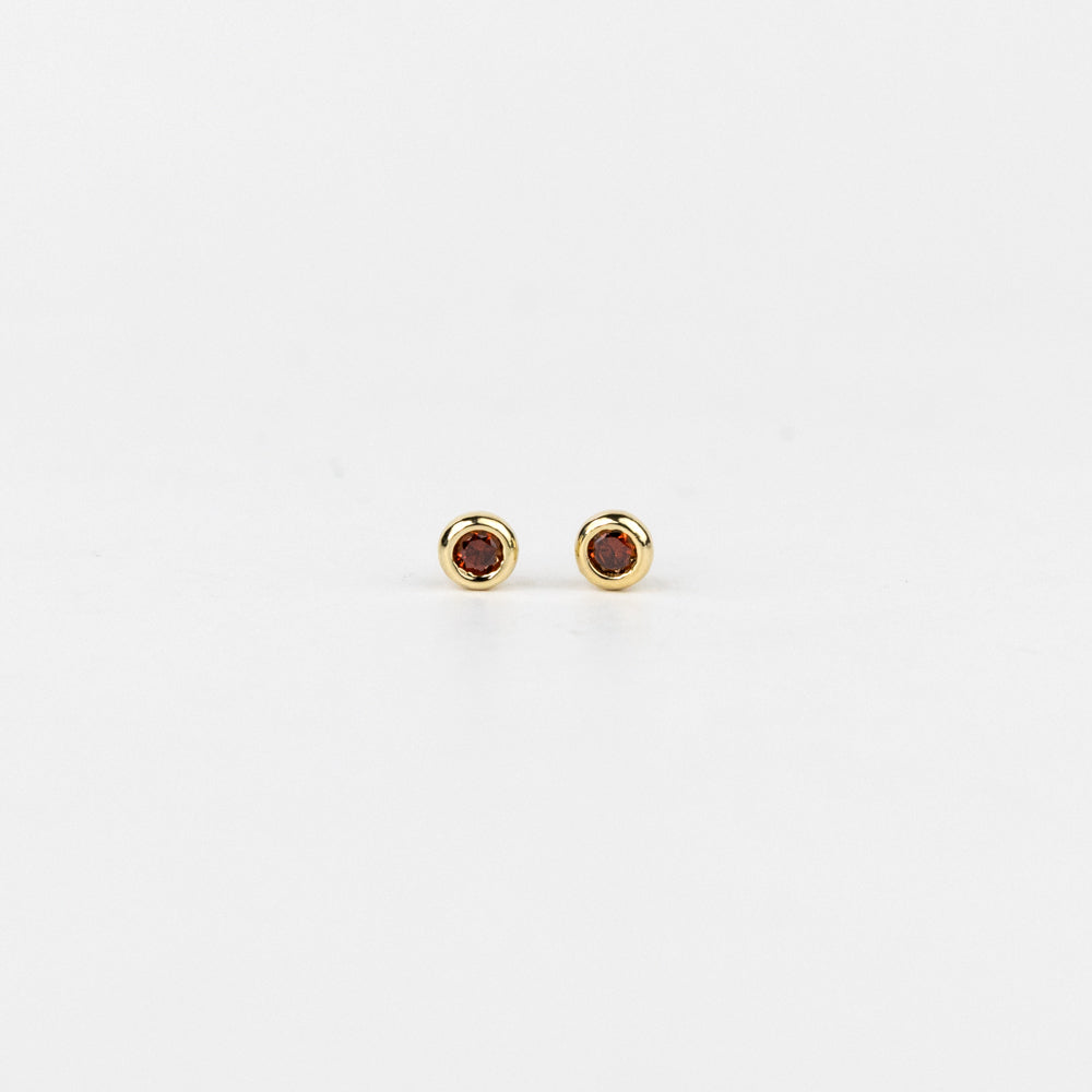 Pair of gold earrings with red gemstones on a white background