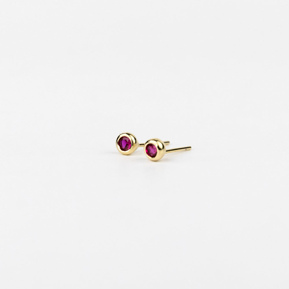 Gold earrings with red gemstones on a white background