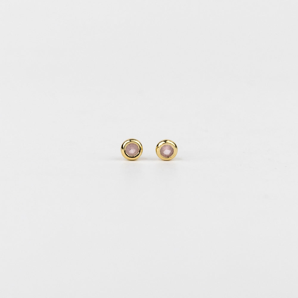 Pair of gold earrings with pink gemstones on a white background