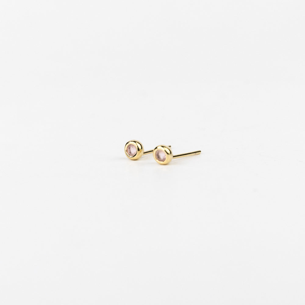 Gold stud earrings on a light beige background