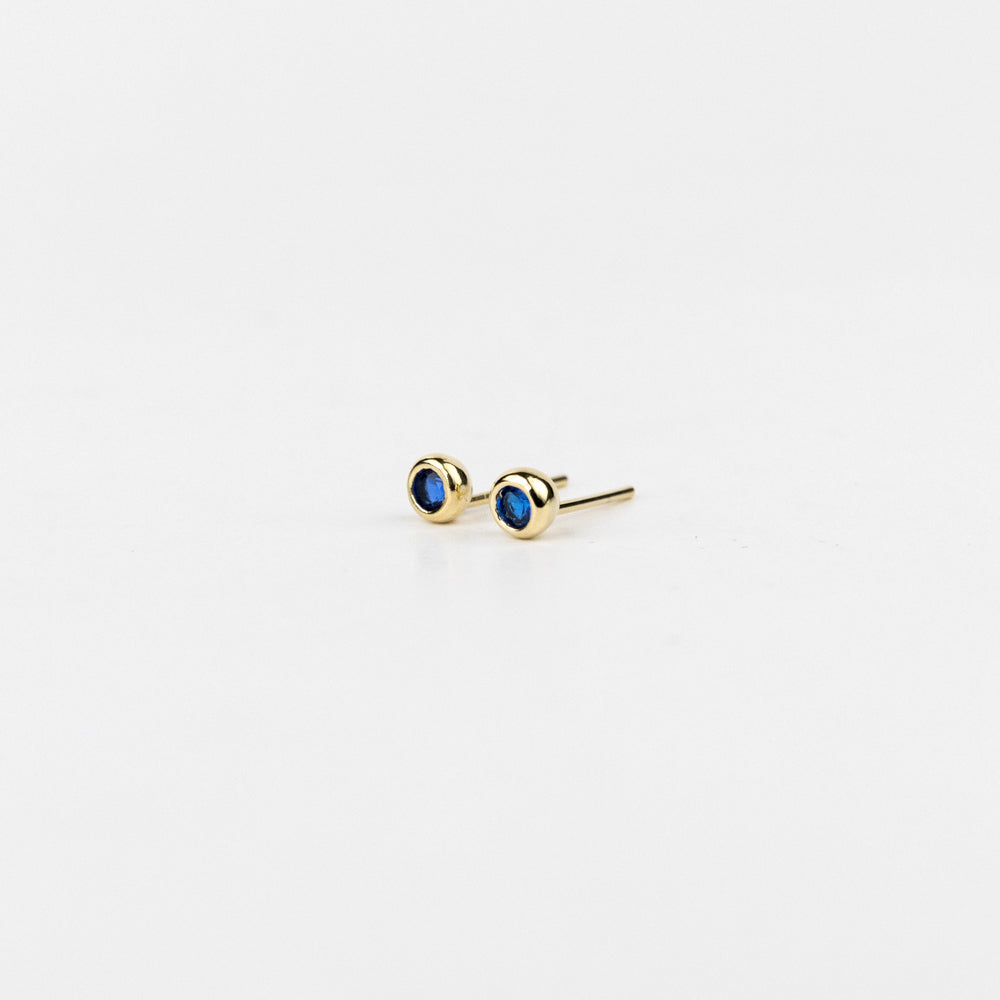 Gold earrings with blue gemstones on a white background