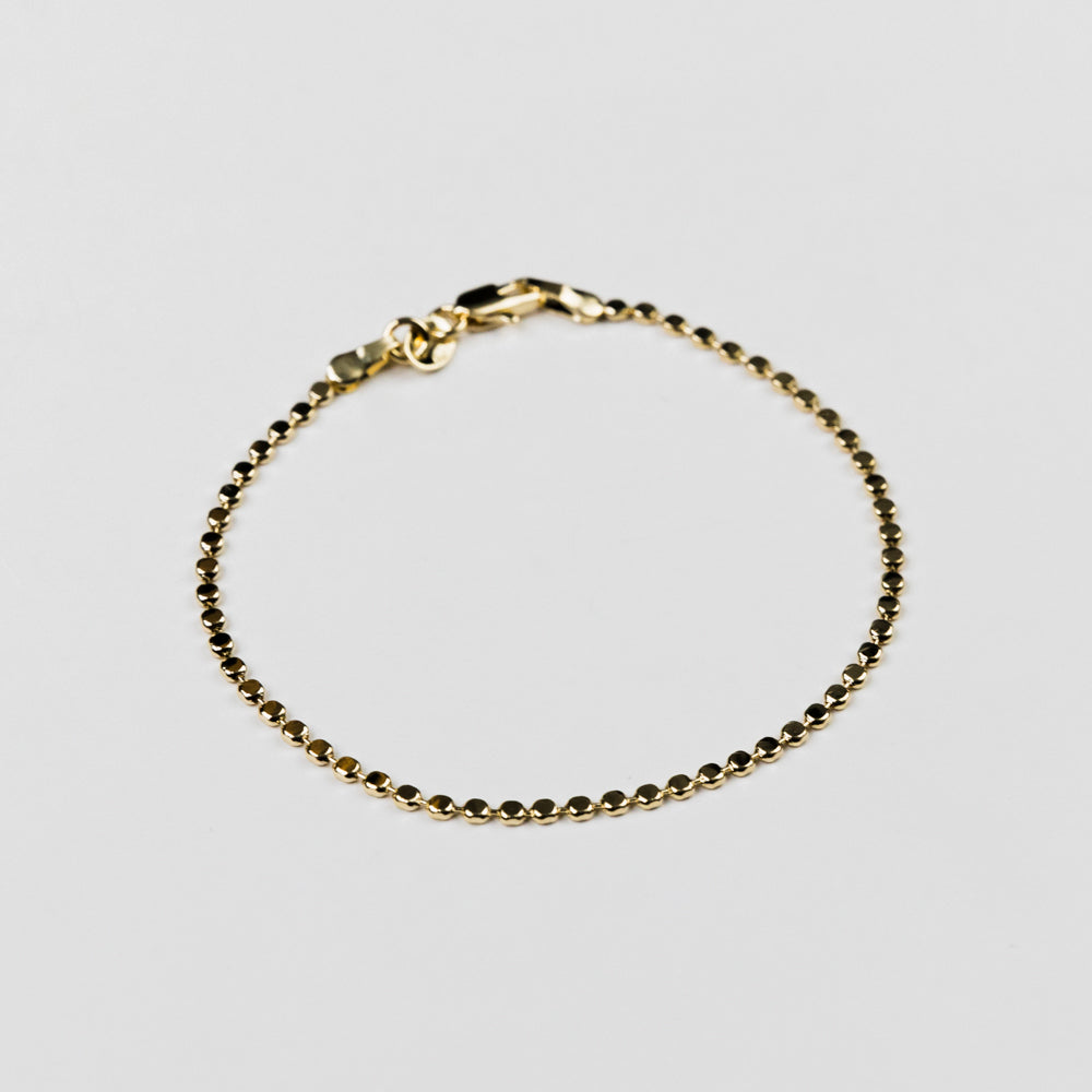 Gold bracelet on a light gray background