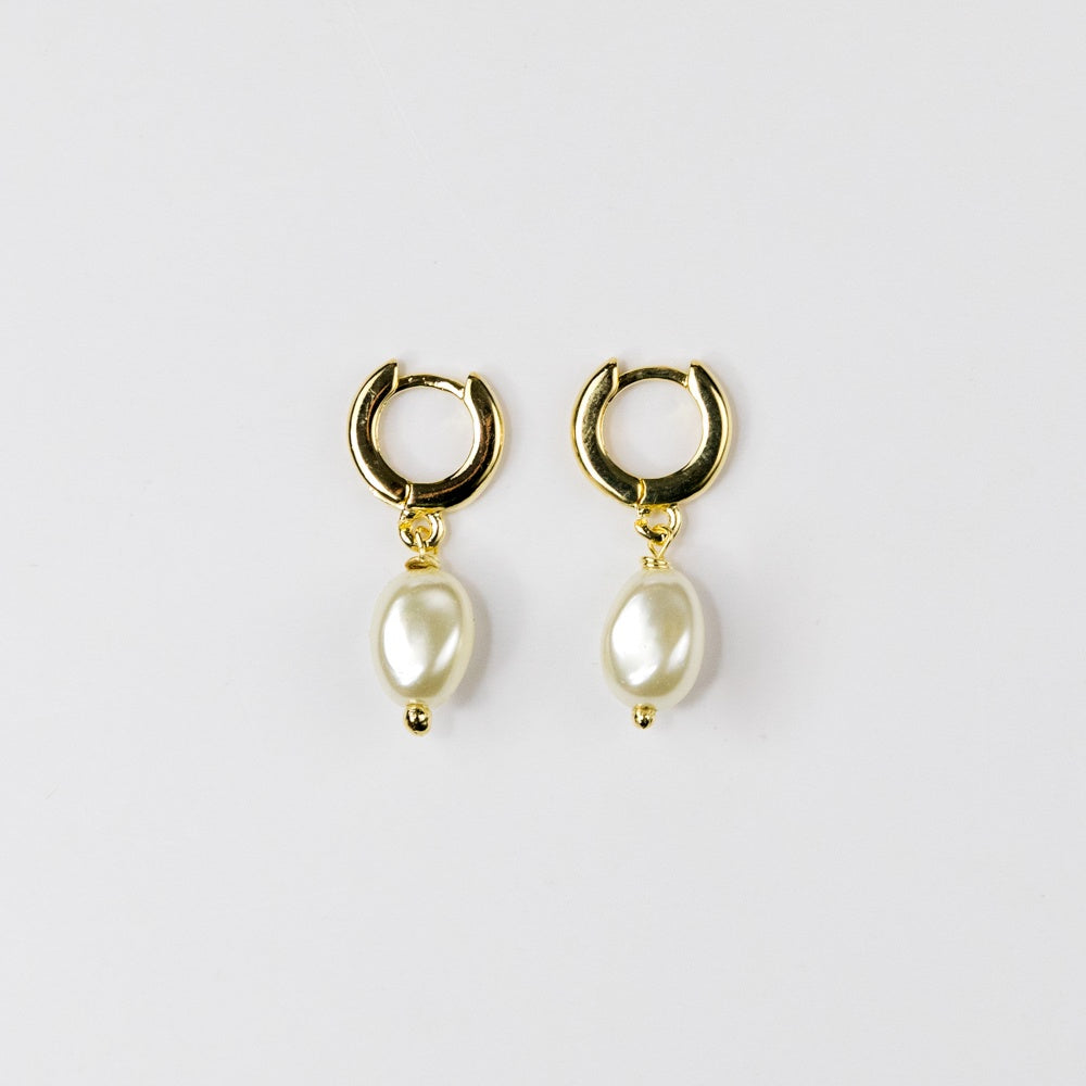 Gold hoop earrings with pearl drops on a light gray background