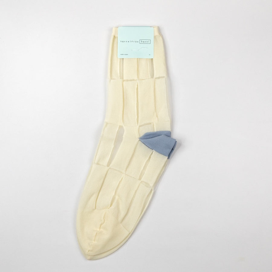 Cream-colored sheer socks with a blue heel on a light gray background