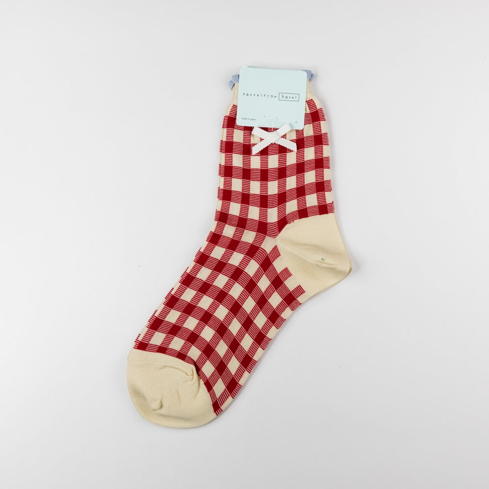 Red and white checkered sock with a bow on a light gray background