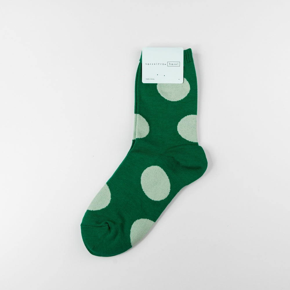 Green sock with white polka dots on a light gray background