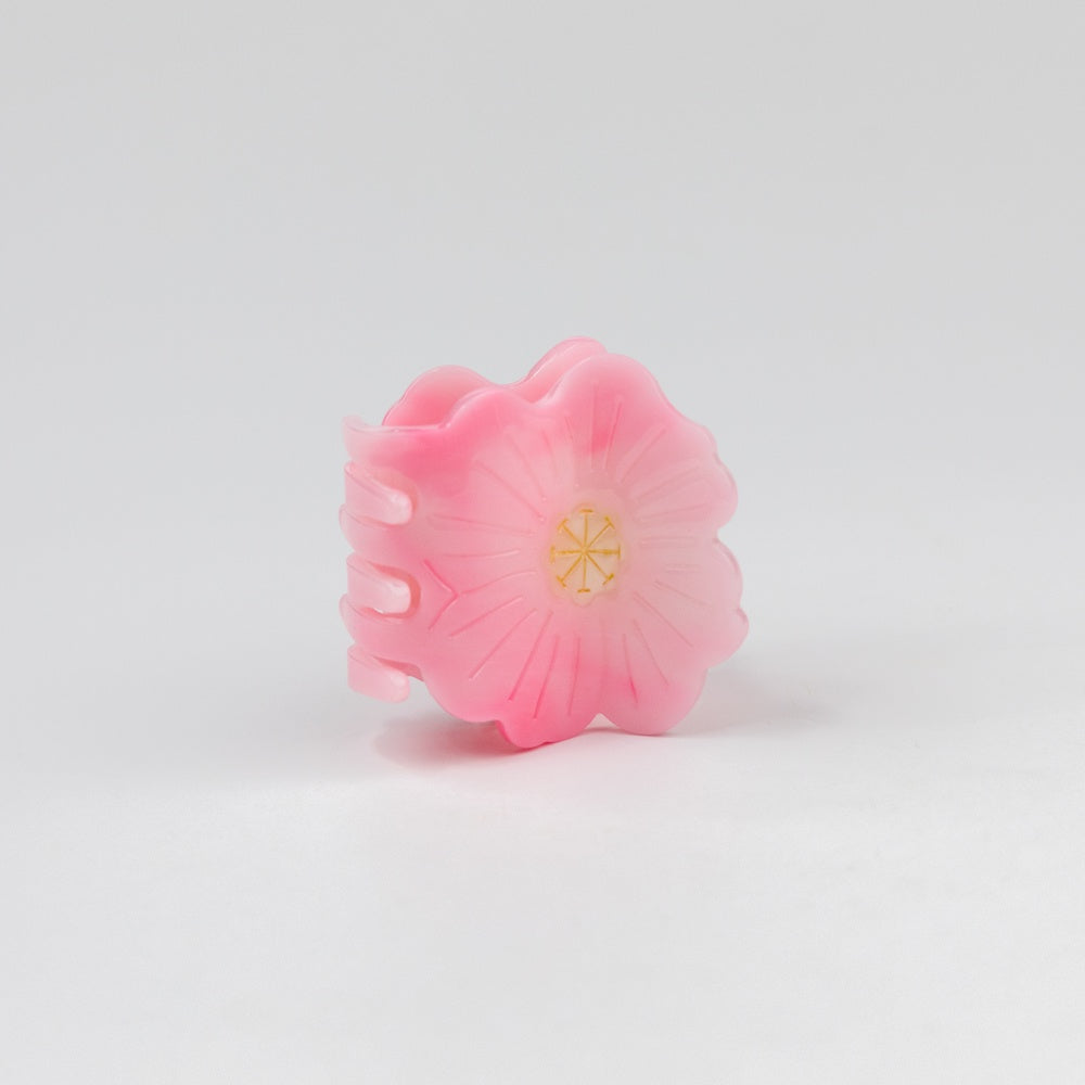 Pink hair clip with a gold center on a white background