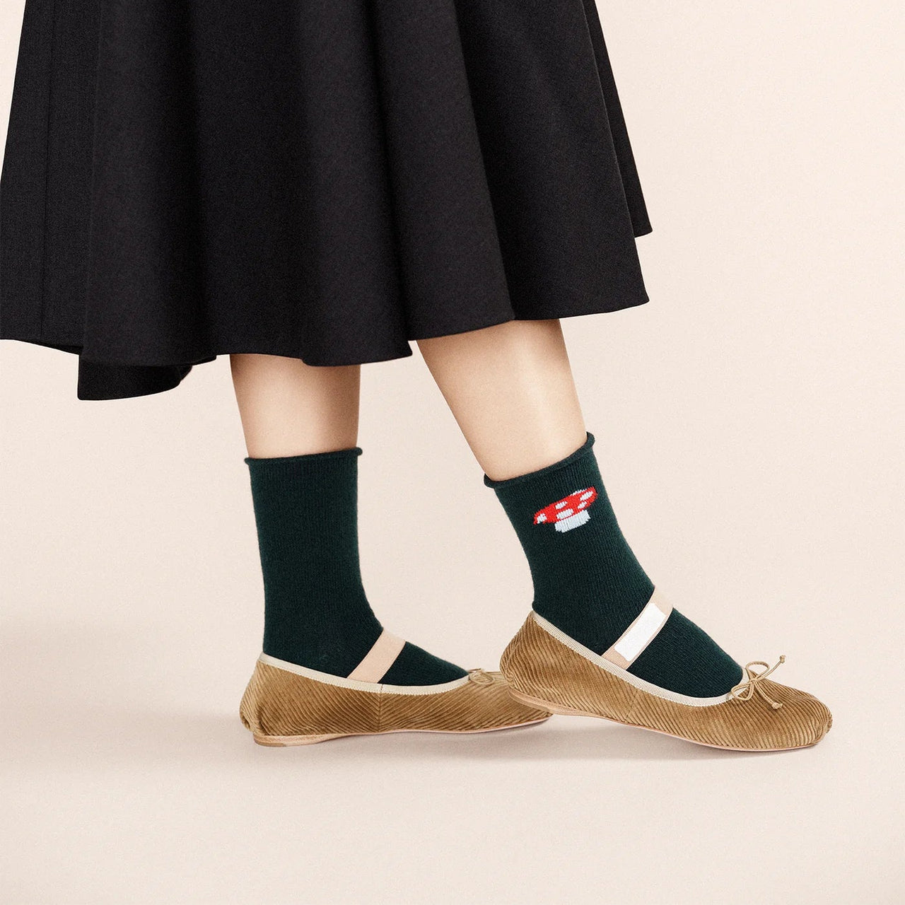 Dark green sock with a red cap mushroom design on a light gray background