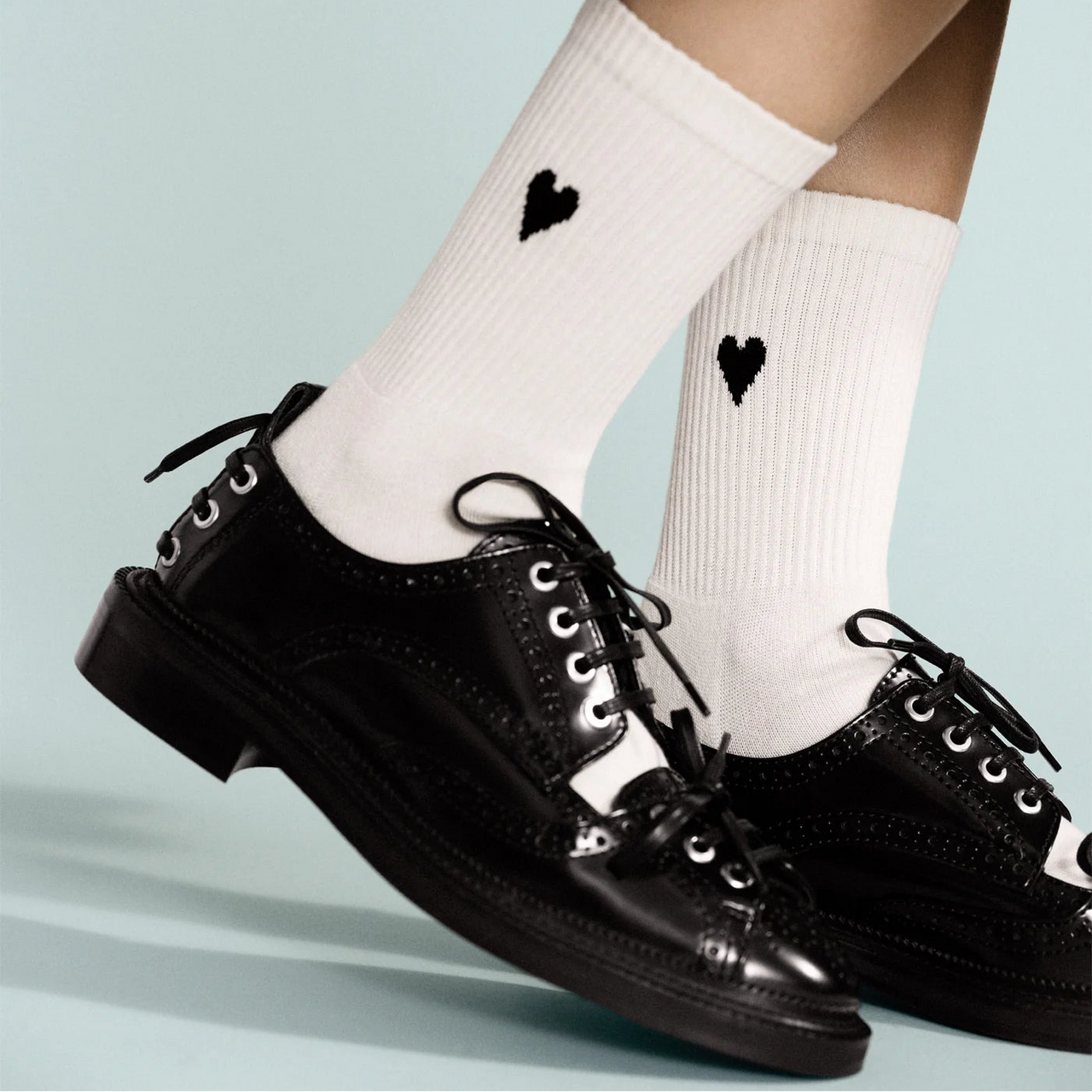 Beige sock with a black heart design on a light gray background