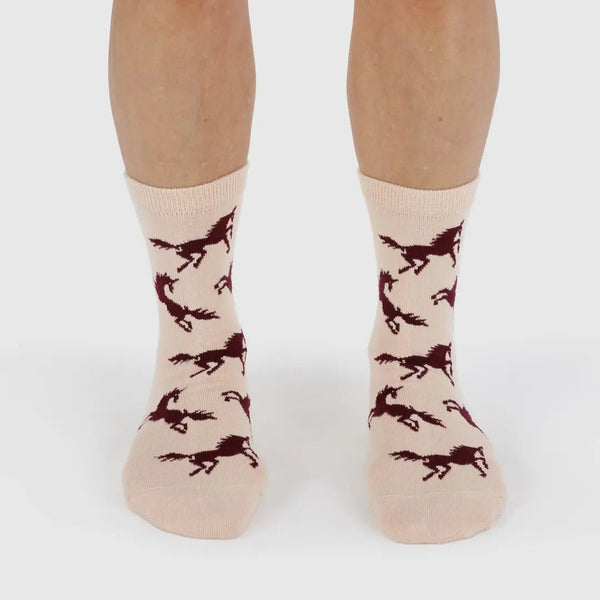 Beige socks with horse pattern worn by a person on a white background