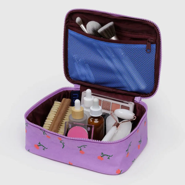 Purple cosmetic bag with makeup items on a light gray background