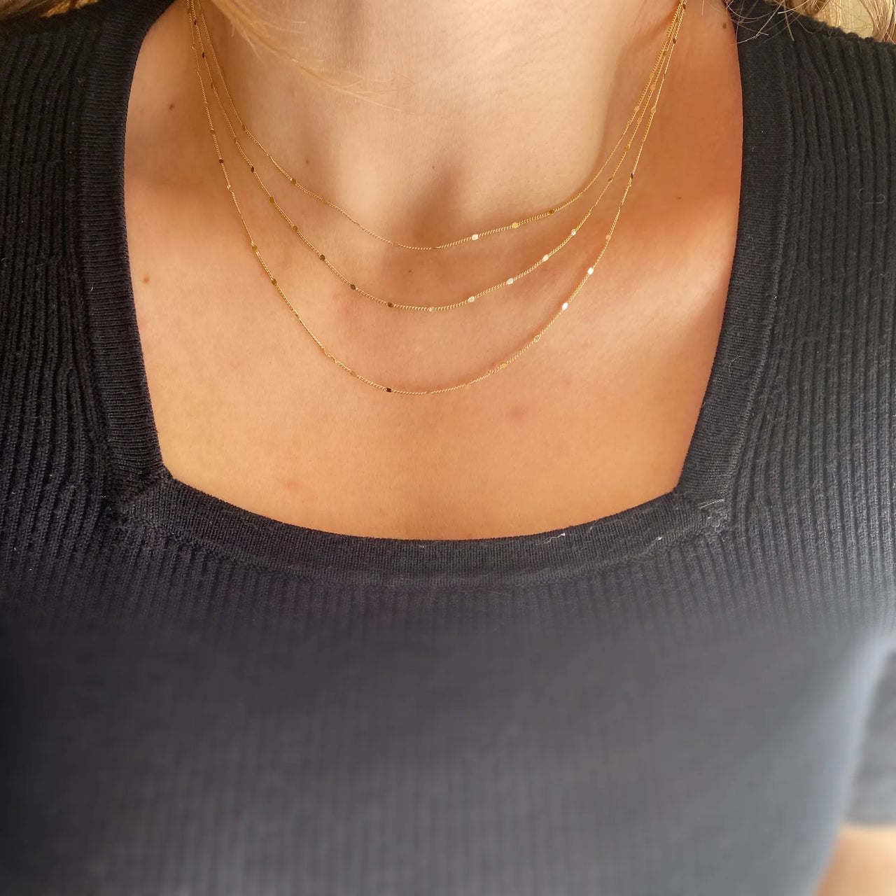 Delicate gold necklace on a light gray background