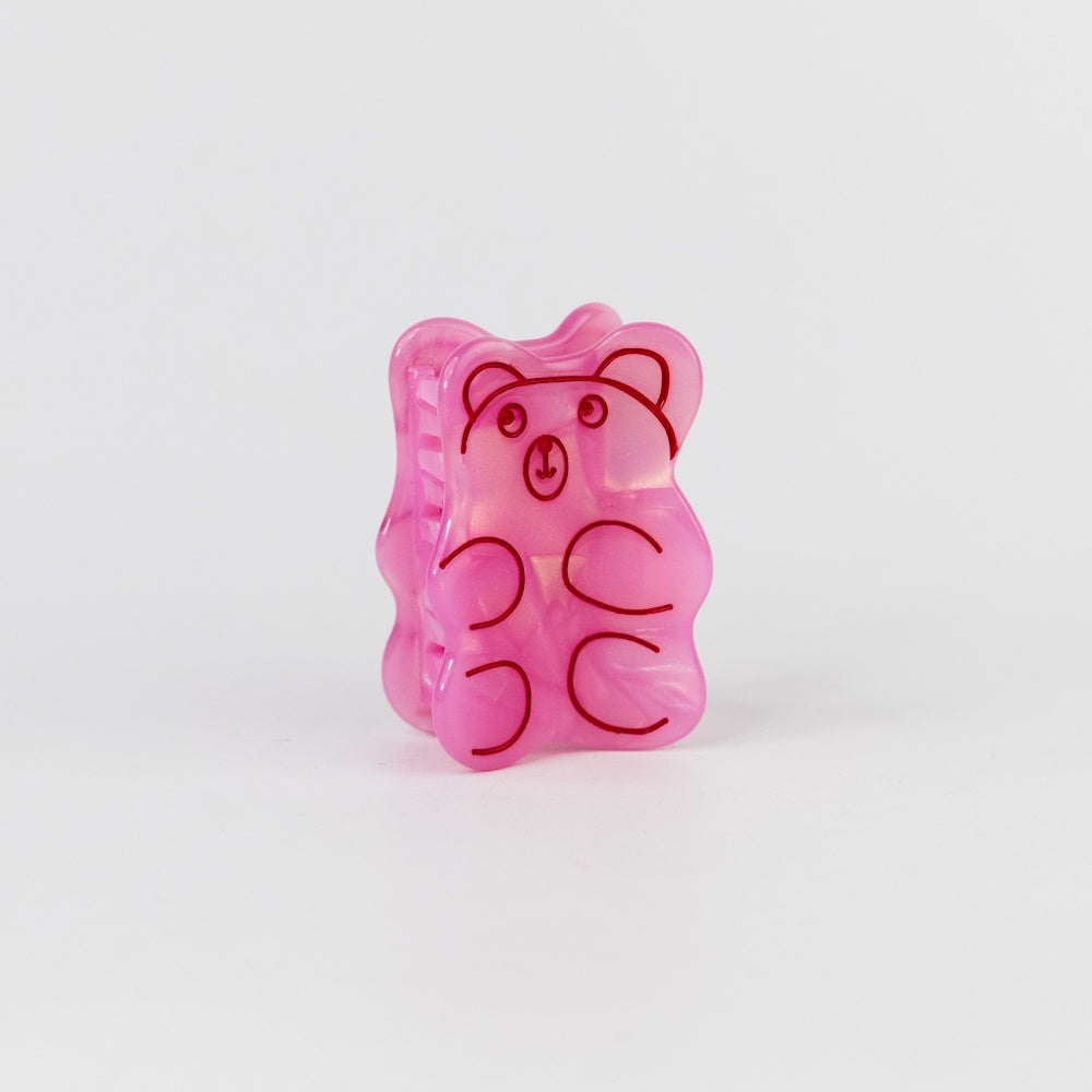 Pink gummy bear-shaped container with a face on a white background