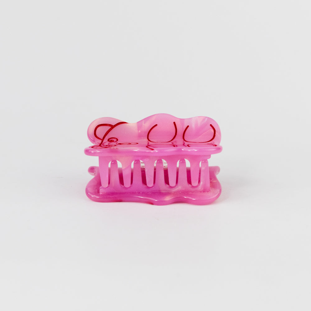 Pink hair clip with a bow design on a white background