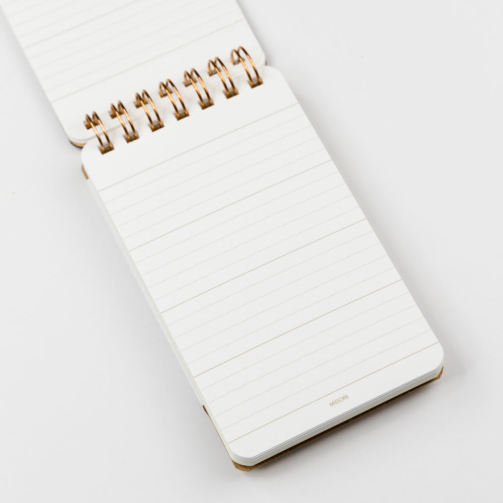 Interior page of small memo notebook with a gold spiral binding on a white background