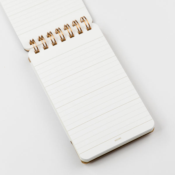 Interior page of small memo notebook with a gold spiral binding on a white background