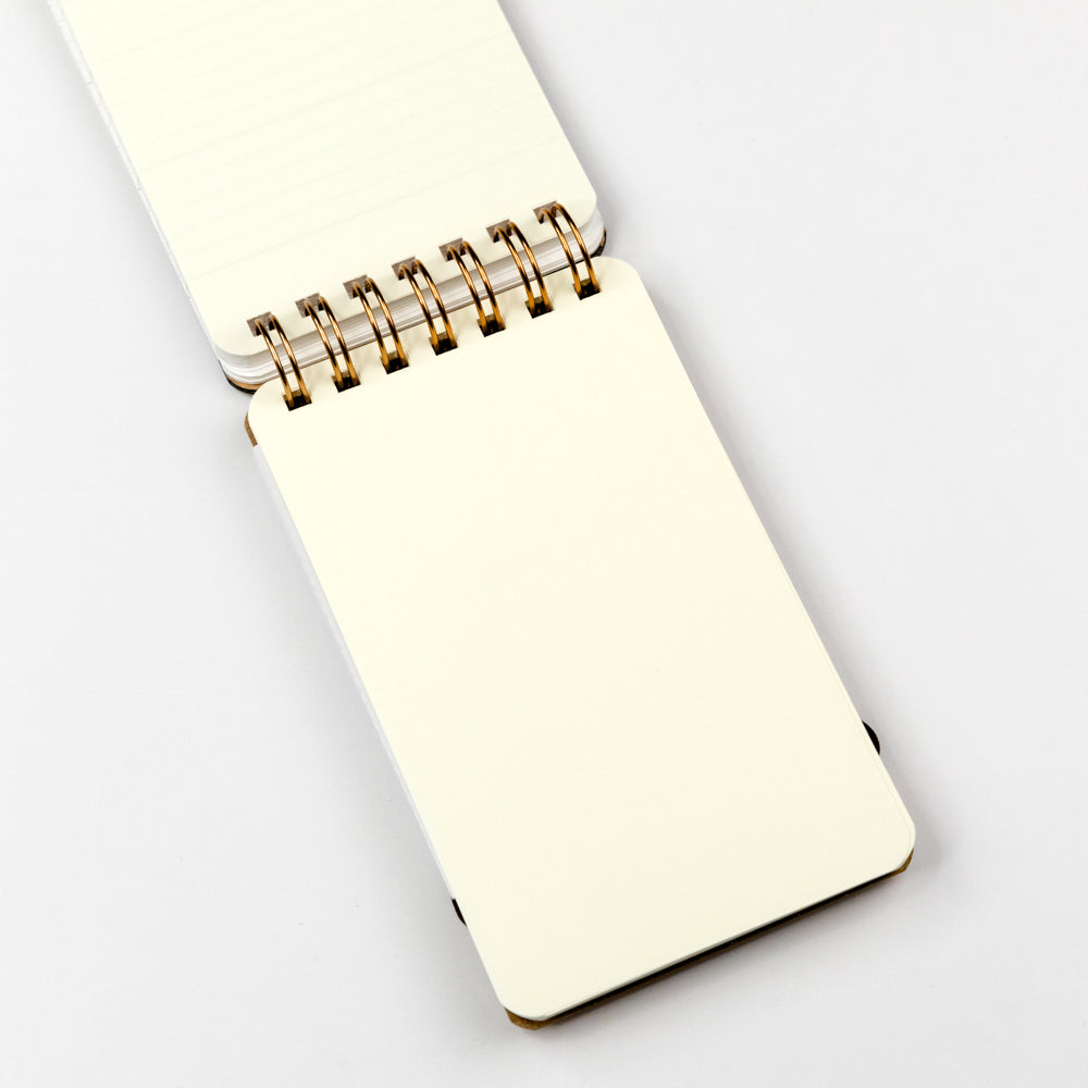 Interior page of small memo notebook with a gold spiral binding on a white background