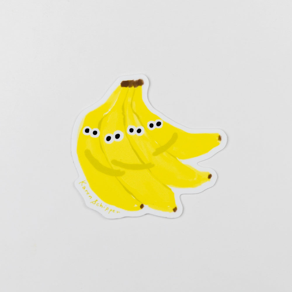 Sticker of a banana with googly eyes on a light gray background