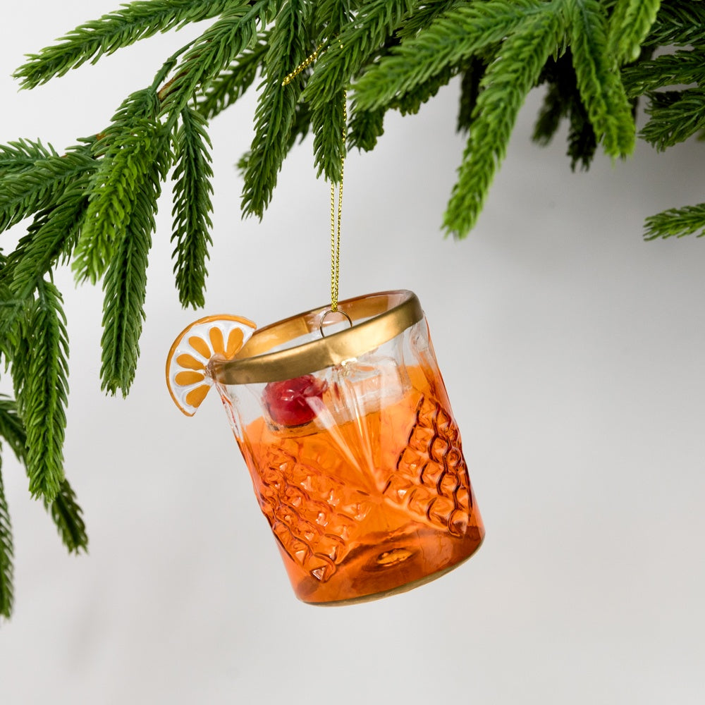 Decorative glass ornament with a gold rim and red berry, hanging from a Christmas tree.