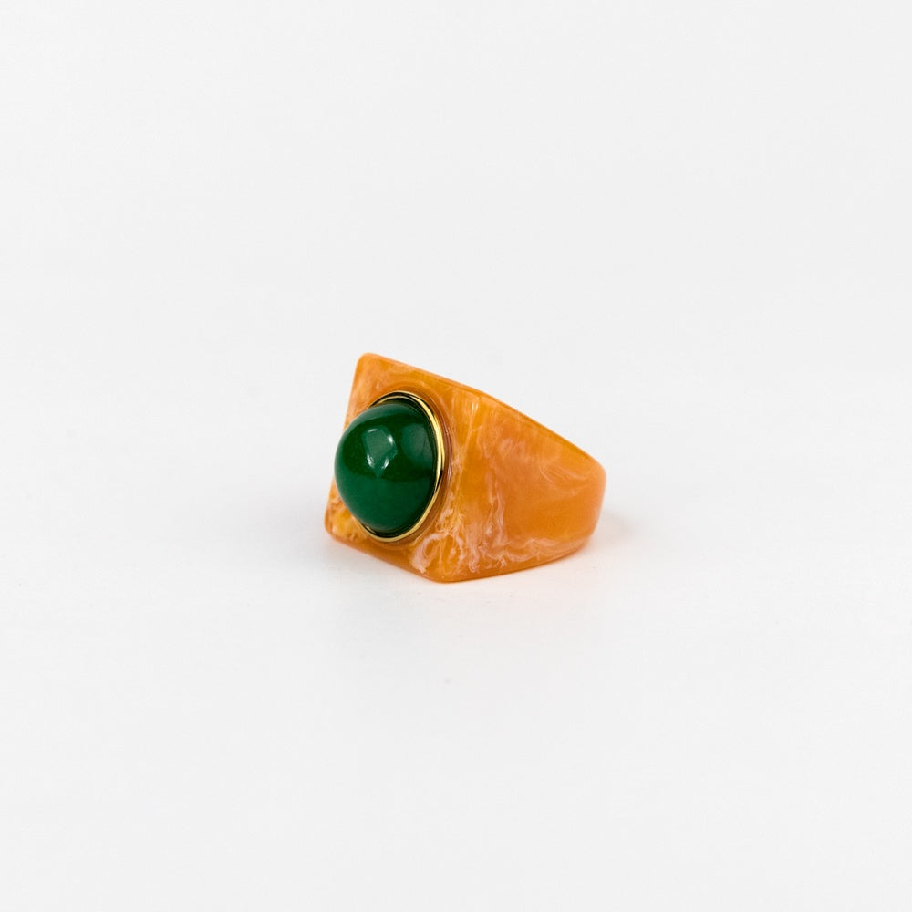Ring with a green gemstone and gold band on a white background