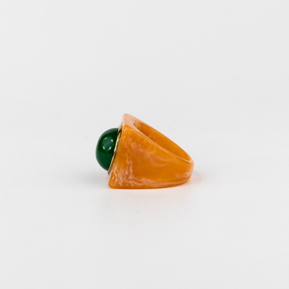 Ring with a green gemstone and orange stone on a white background