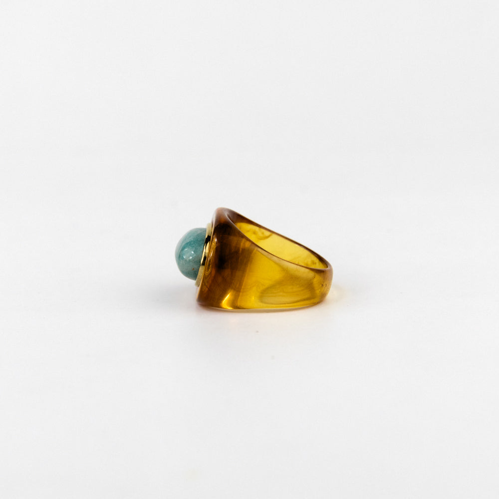 Ring with a yellow band and turquoise bead on a white background