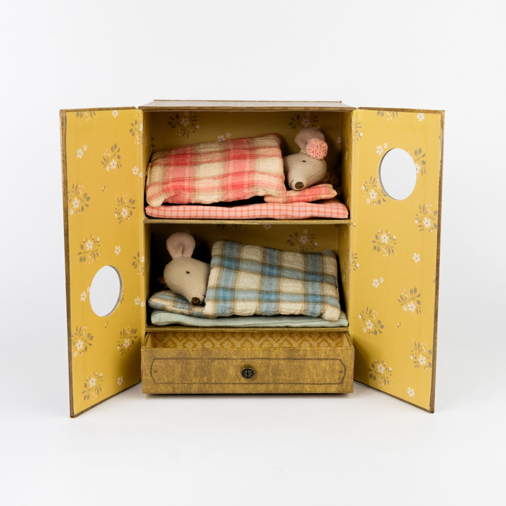 Toy mouse with plaid blankets inside a decorative box on a white background