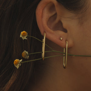 Close-up of an ear with a pair of elongated hoops