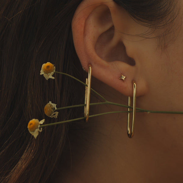 Close-up of an ear with a pair of elongated hoops