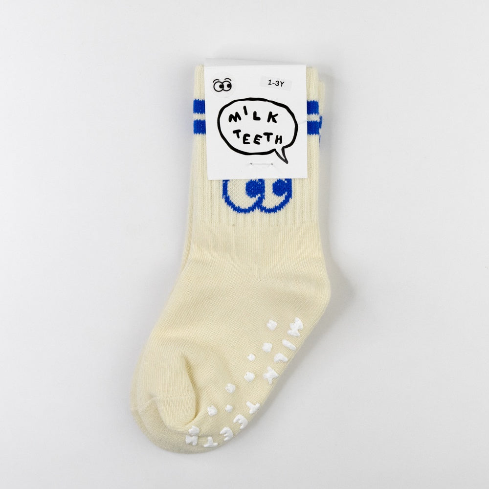 Pair of beige socks with blue accents and white dots on a light gray background