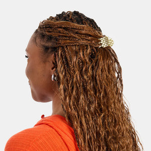 Woman with braided hair wearing an orange top on a white background