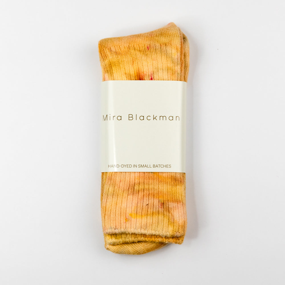 Pair of orange tie-dye socks on a white background