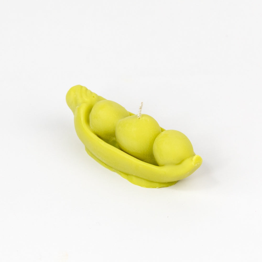 Pea pod candle with three peas on a white background