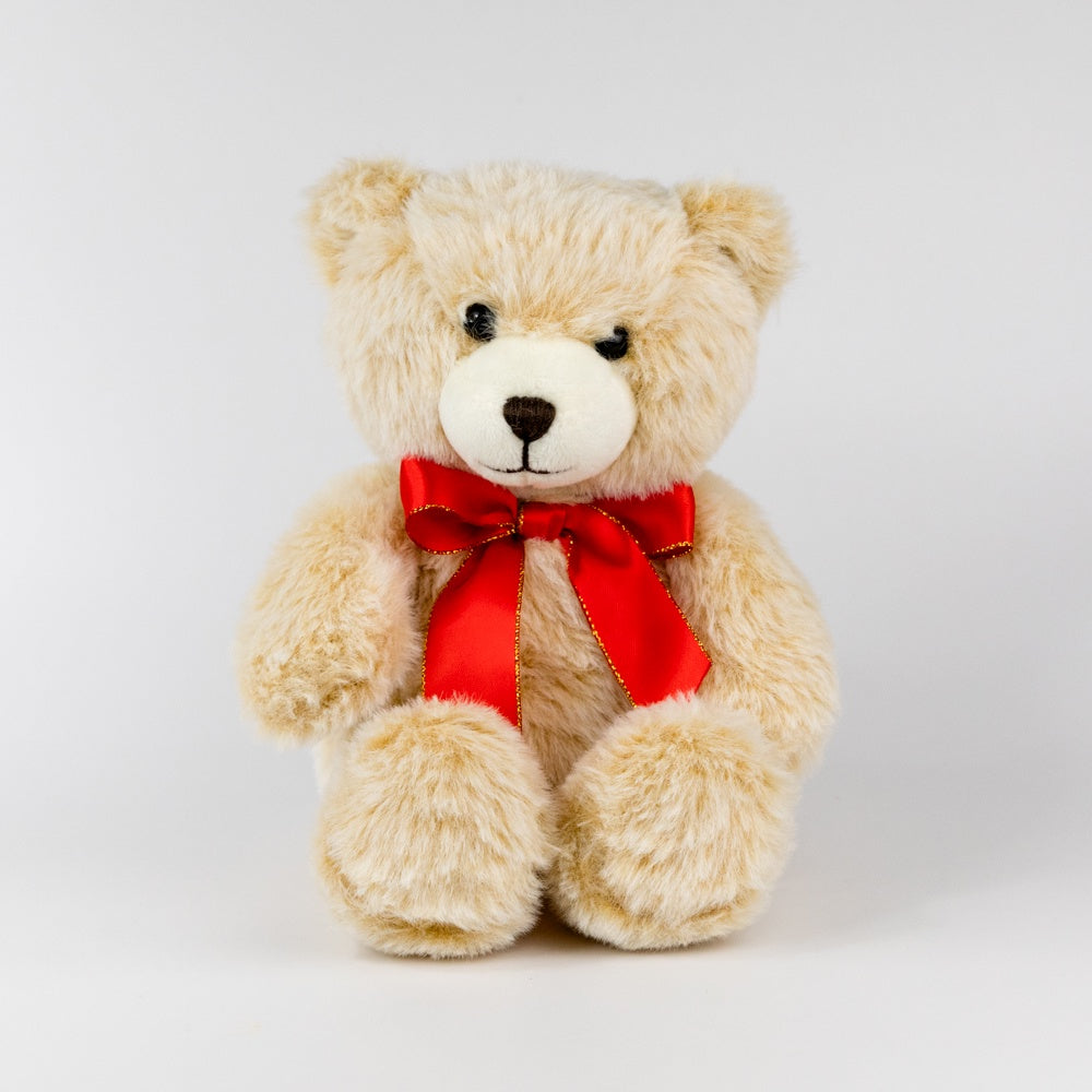 Beige teddy bear with a red bow on a white background