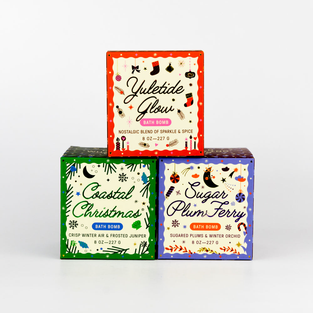 Three bath bomb boxes with festive designs on a white background