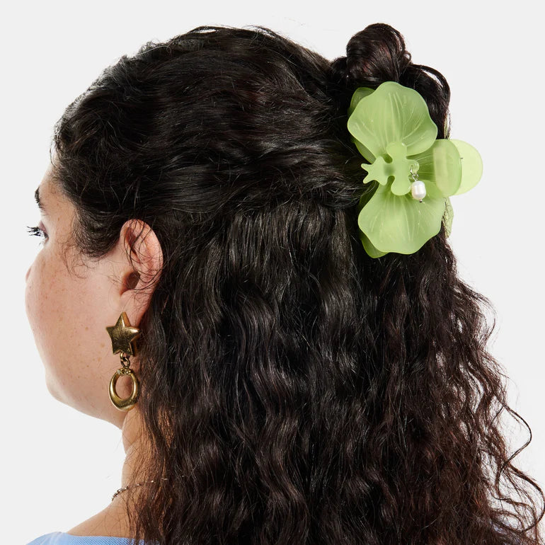 Green orchid-shaped hair clip with a pearl on a white background