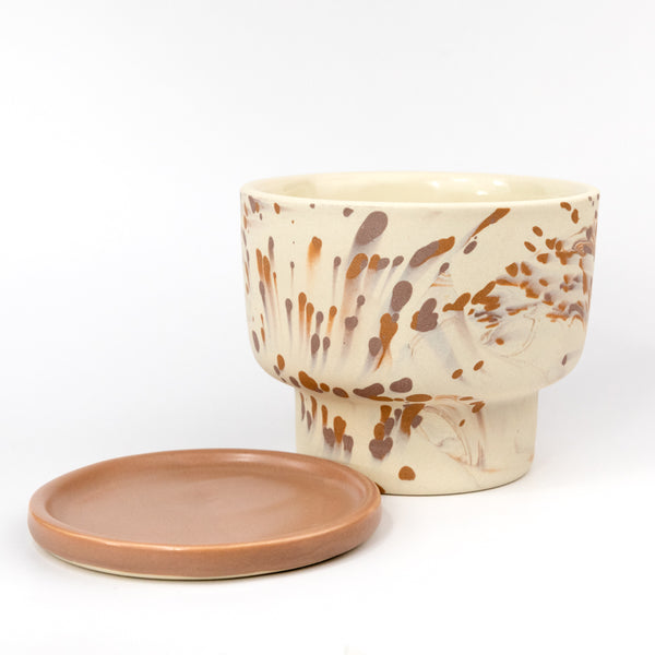 Ceramic cup with brown abstract patterns and matching saucer on a white background