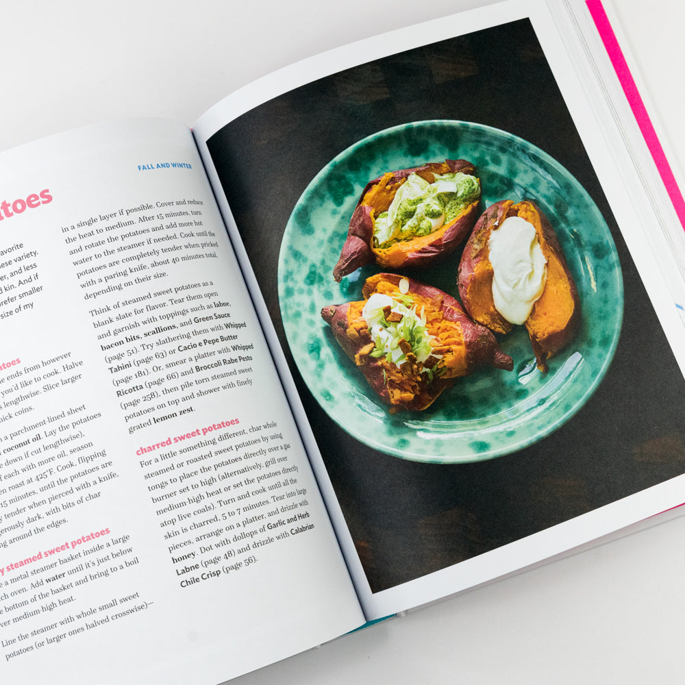 Open cookbook showing a plate of roasted sweet potatoes with toppings on a green plate.