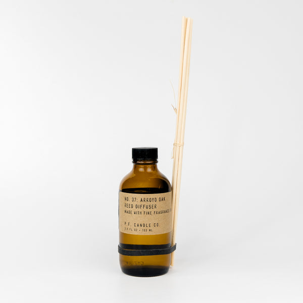 Brown bottle with black cap and wooden sticks on a white background
