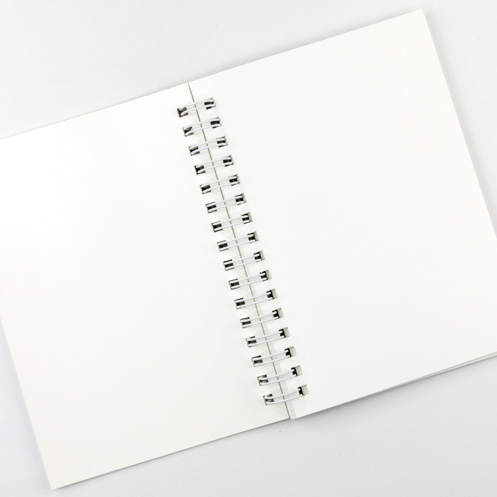 Open notebook with white pages and a metal binding on a light gray background