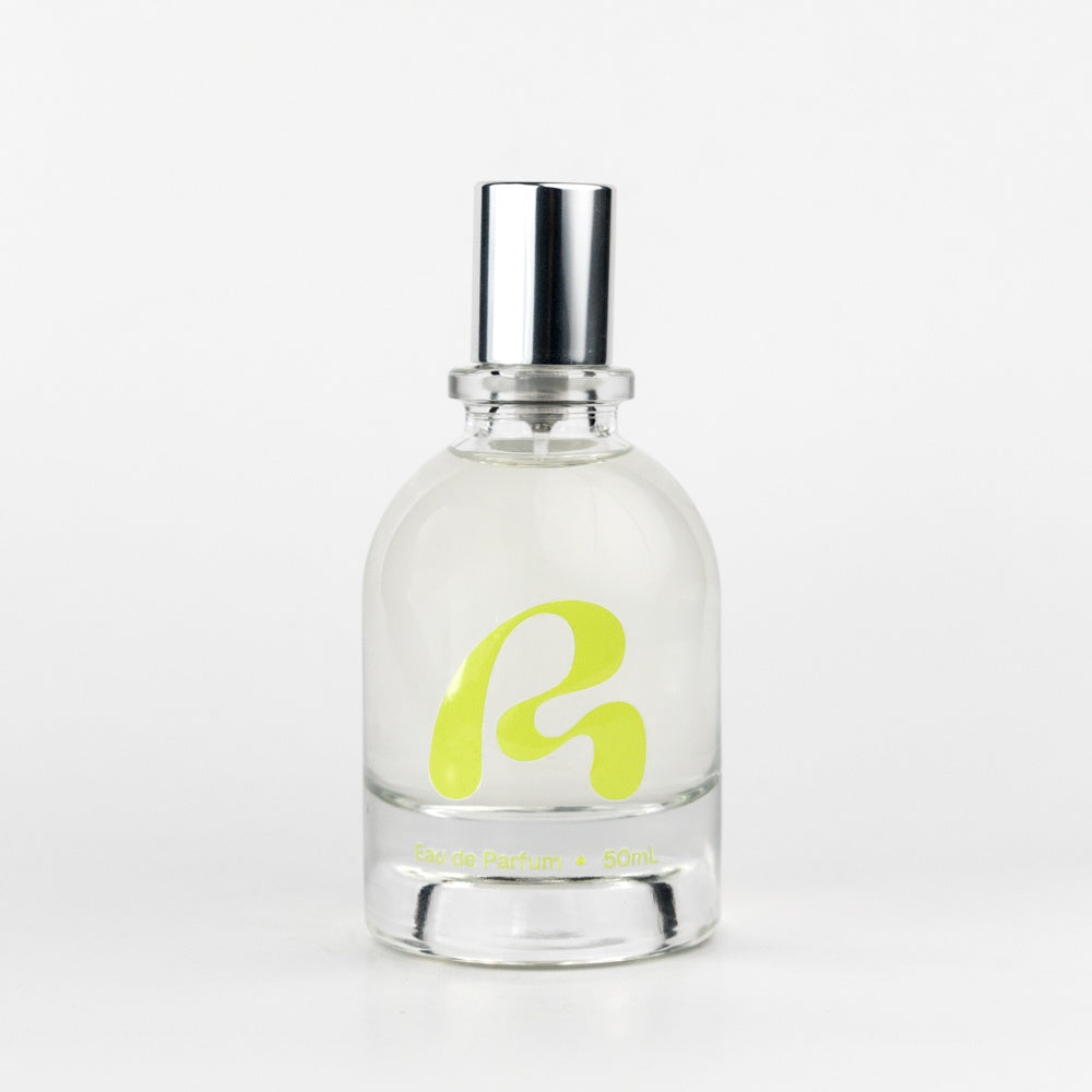 Clear perfume bottle with a silver cap and yellow logo on a white background