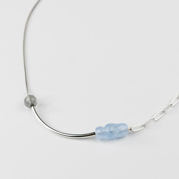 Necklace with a blue gemstone on a light gray background