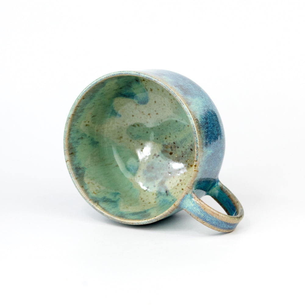 Ceramic mug with green and blue glaze on a white background